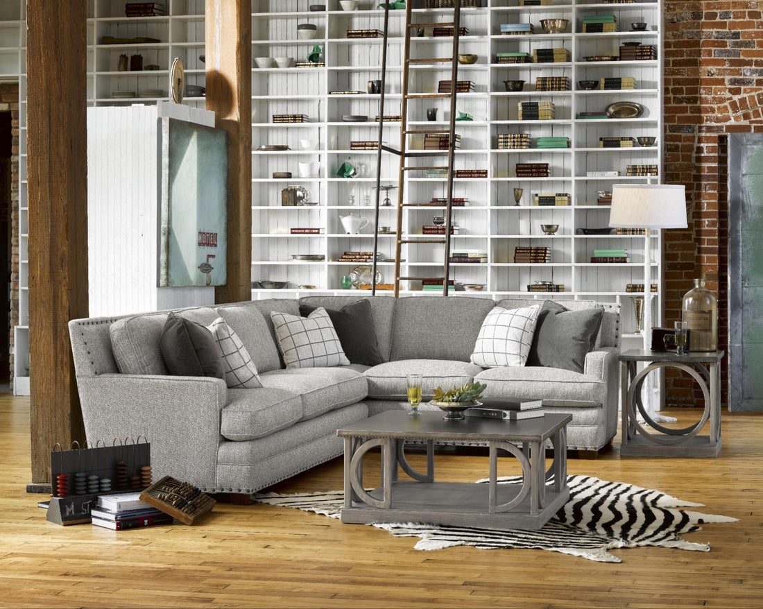 A light gray couch with patterned pillows, in a rectangular living room 