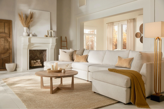An off-white sectional with a coffee table, fireplace, and floor lamp 