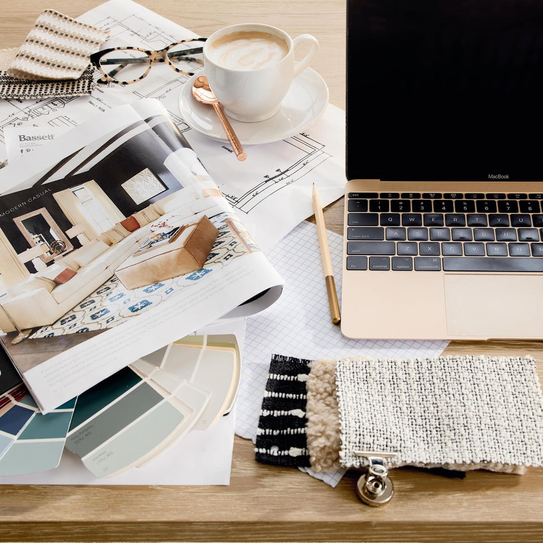 A laptop, catalog, and fabric and color samples