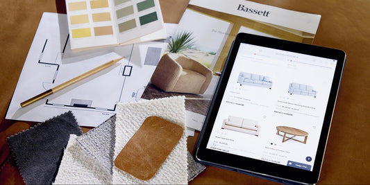 An iPad with sofas and a coffee table next to paint samples and sketches