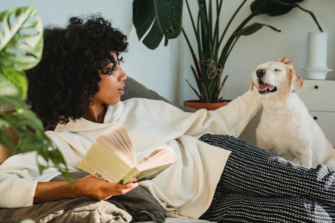 A girl reading a book and petting her dog