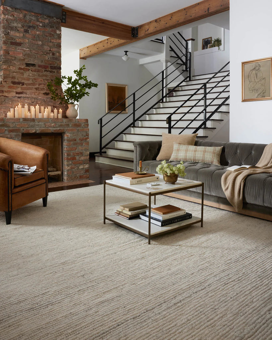 A cozy gray couch, light-colored rug, white coffee table, and brown chair 