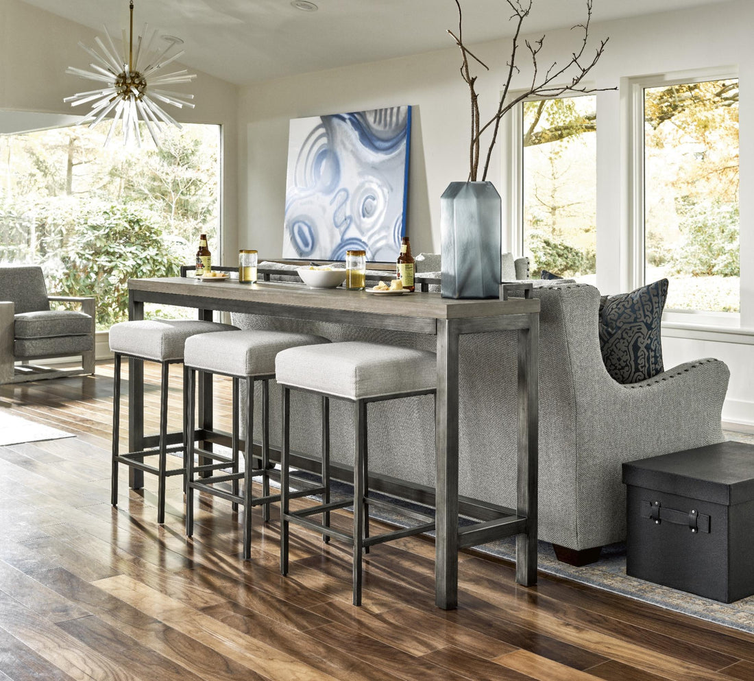 A gray couch and a bar table with three stools