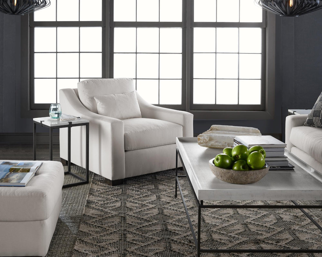 A white chair set, coffee table, and two layered rugs 